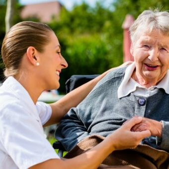 Assistante sociale qui s'occupe d'une femme âgée en fauteuil roulant