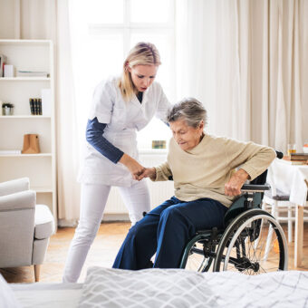 Aide soignante qui aide une femme âgée en fauteuil roulant