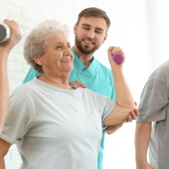 Animateur.trice médico-social.e en gérontologie avec une femme âgée faisant du sport