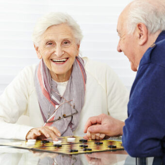 Couple de personnes âgées heureux, jouant aux dames