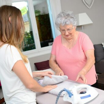 Technicienne d'intervention sociale et familiale qui repasse le linge d'une femme