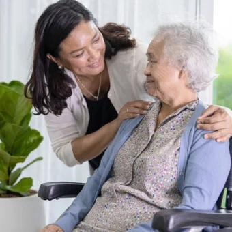 Aide soignante à domicile qui parle avec une femme âgée en fauteuil roulant
