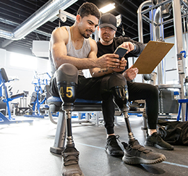 un homme avec deux jambes artificielles dans une salle de sport, avec un coach