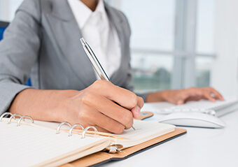 Une femme, dans son bureau, qui prend des notes