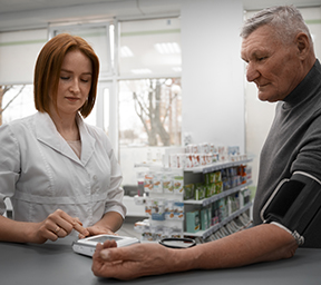 Une pharmacienne qui prend la tension d'un homme âgé.