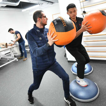 éducateur médico-sportif qui entraine un élève avec des ballons de médecine