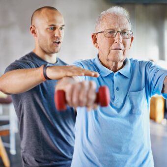 Coach APA faisant faire un exercice de sport à un homme âgé