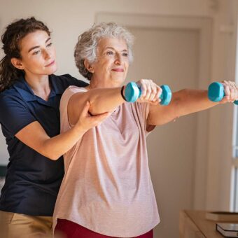 Educatrice APA aidant une senior dans ses exercices physiques