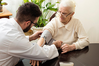 Médecin gériatre qui prend la tension d'un homme âgé