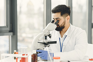 Technicien en microbiologie avec miscroscope dans un laboratoire