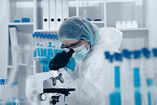 Technicienne en biotechnologies qui analyse avec un microscope