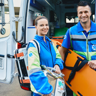 emergency medical technicians standing near ambulance. personnel of emergency service with first aid medical equipment