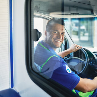 ems. smiling ambulance driver sitting in cab of ambulance vehicle, back view