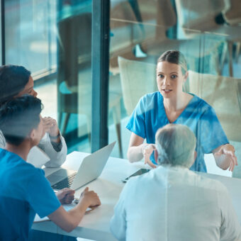 medical team, doctors and meeting with a laptop for a discussion, planning or research at table. men and women healthcare group talking about communication strategy, virus or surgery in a hospital